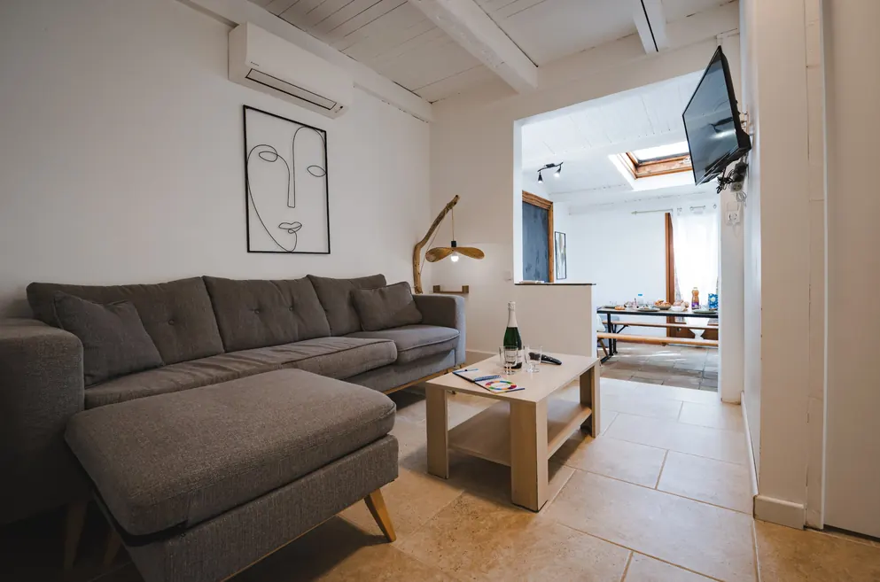 Salon climatisé avec canapé d’angle et TV dans la Maison d’Edith, camping au Pradet
